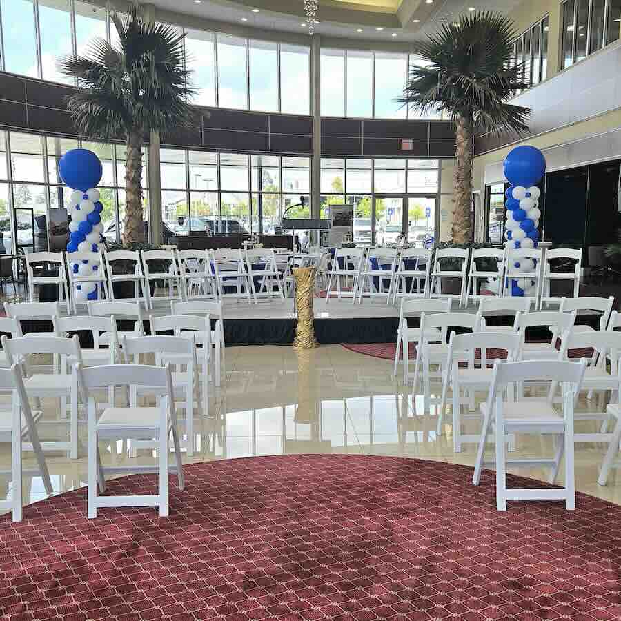 Indoor event setup with white chairs and stage