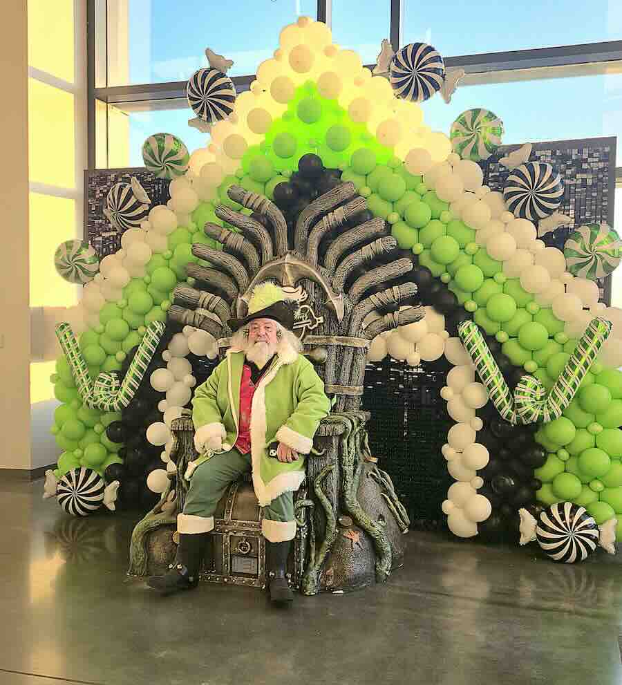Santa in green suit on festive balloon throne