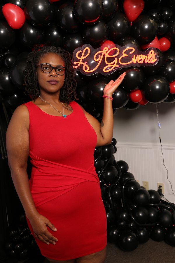 The owner of LJG Events, Kesha, standing in front of one of her branded black and red balloon tree.