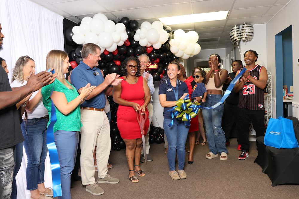 A group photo of Kesha cutting the ribbon at her LJG Events ribbon cutting ceremony with people clapping and smiling all around her.