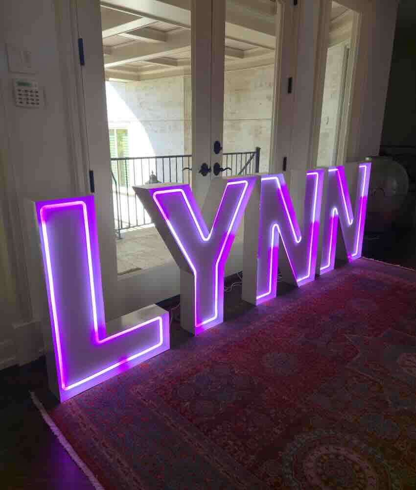 Purple neon letters spelling LYNN on a patterned rug