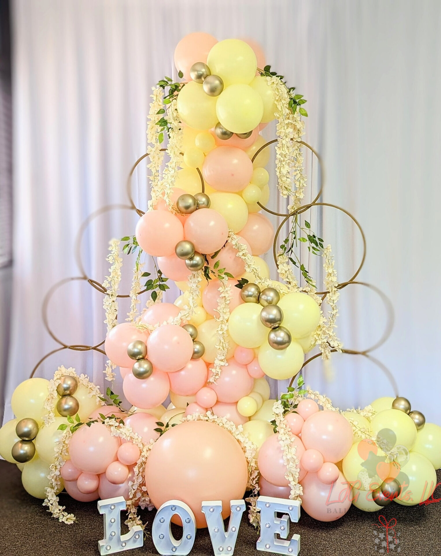 A beautiful balloon sculpture with gold rings around it and the words "LOVE" under it.