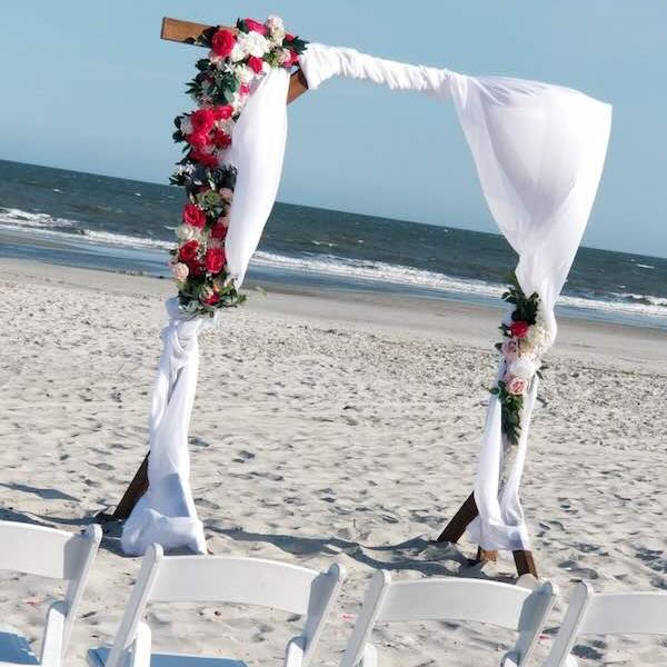 Beach wedding arch with flowers and fabric decor.