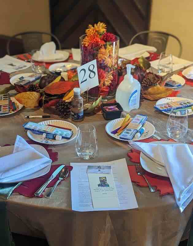 Fall-themed table setting with paint supplies and sanitizer.