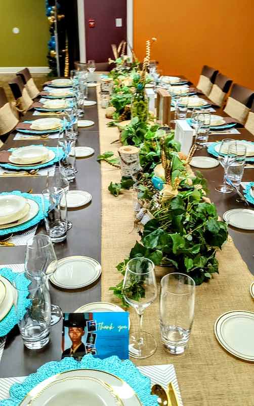 A beautiful long table that is decorated with turquoise table settings and decorations.