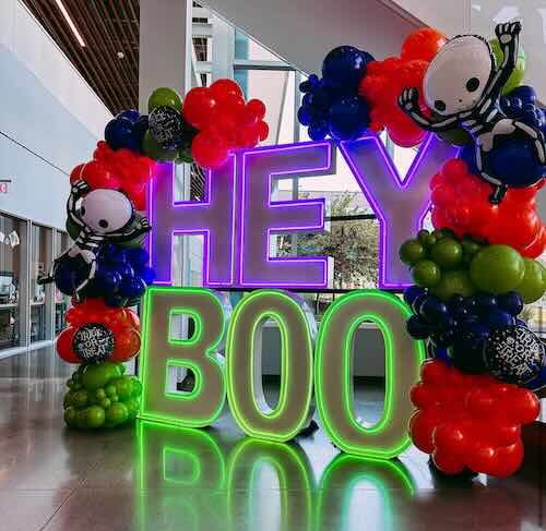 Hey Boo neon sign with colorful balloon decorations.