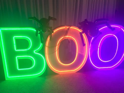 Neon 'BOO' sign with plastic spiders.